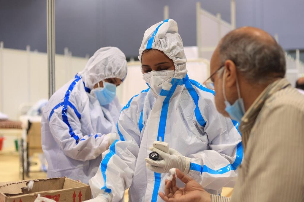 A health worker in PPE checking a patient's oxygen level