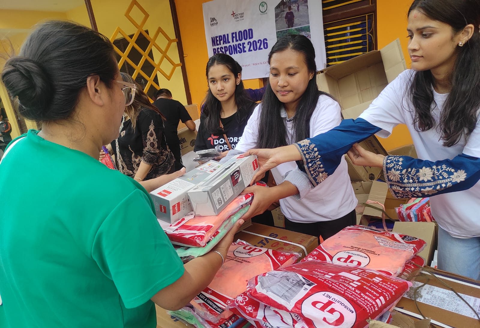 Volunteers handing mosquito nets to a flood-affected resident